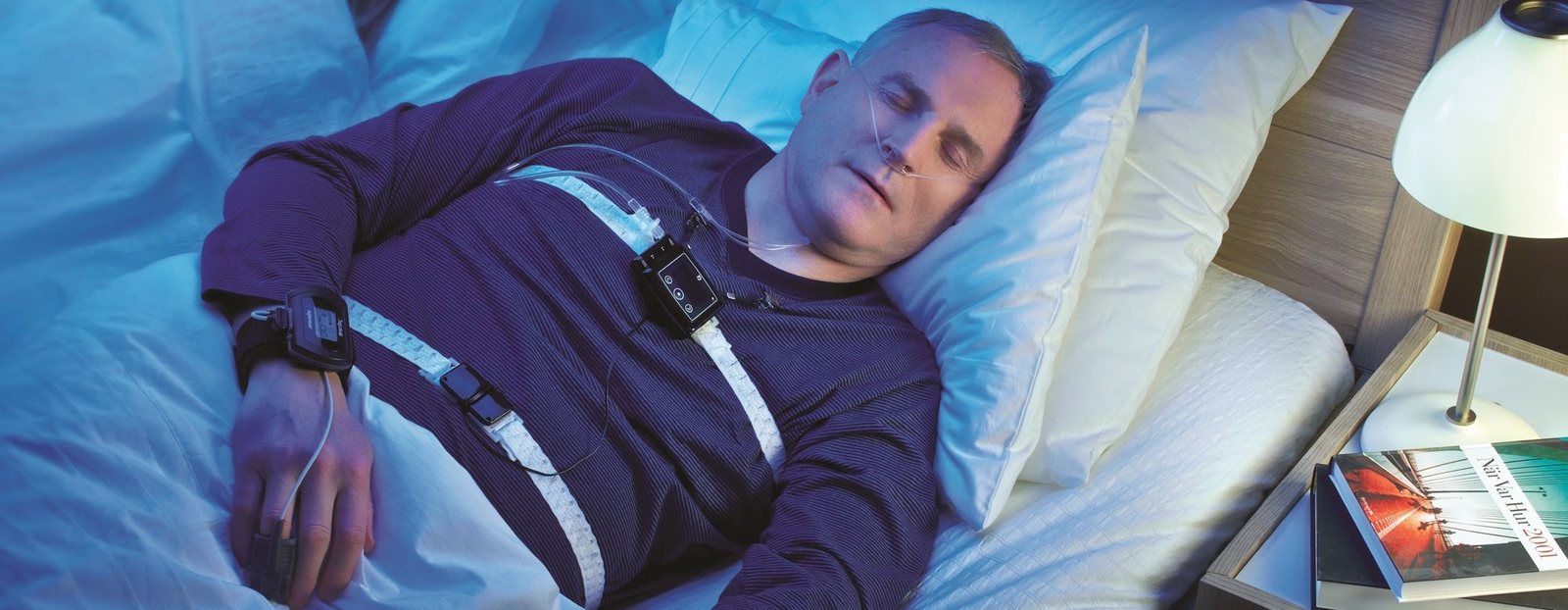 A man asleep at home wearing a portable sleep study device