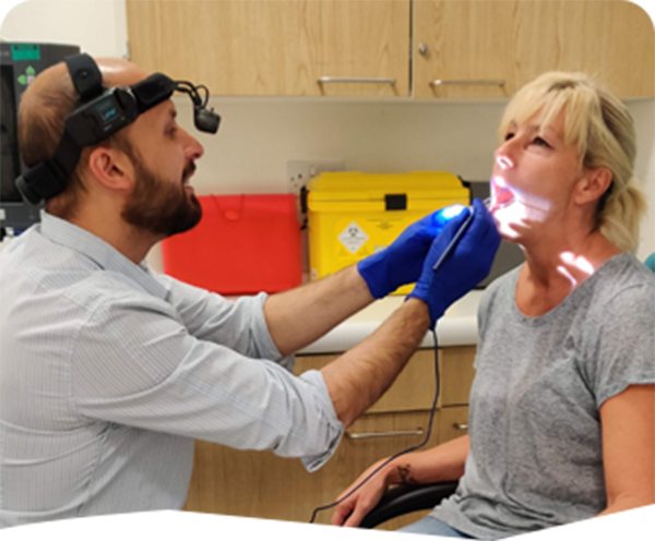 A clinician examining a patient's throat with a light